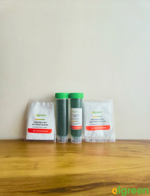 Two 100ml Live Spirulina Culture tubes with green screw caps flanked by two white Proprietary Nutrient Blend packets on a wooden surface